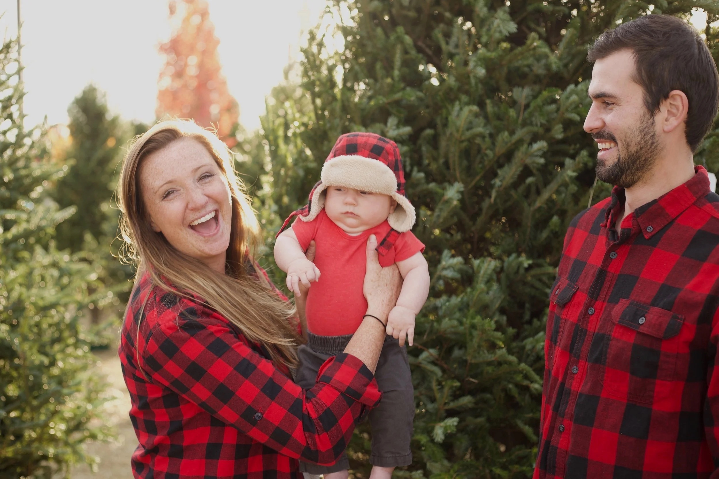 Parents and baby smiling among the trees